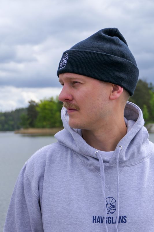 Mörkblå Havsglans Beanie sedd från sidan vid vattnet