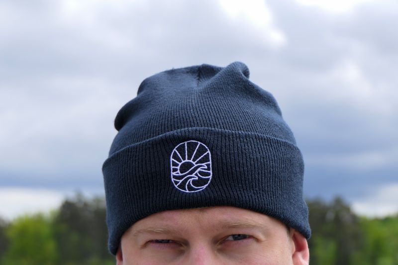 Närbild på broderad Havsglans-ikon på mörkblå Beanie