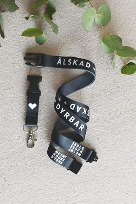 Nyckelband i svart: ÄLSKAD, VÄRDEFULL, DYRBAR