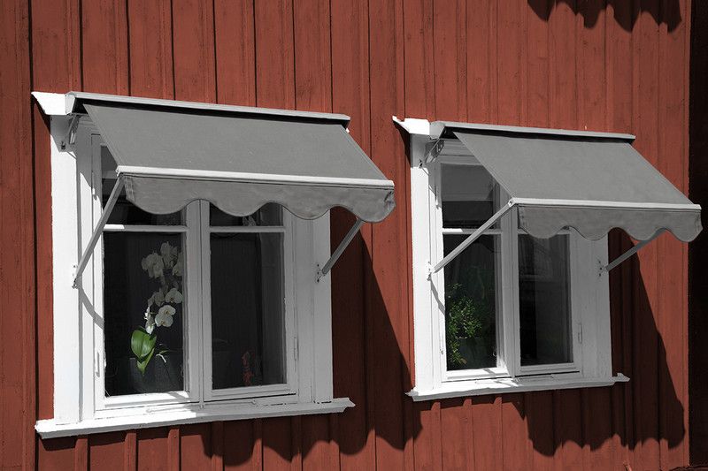 Enfärgad grå markisväv på metervara på falurött hus