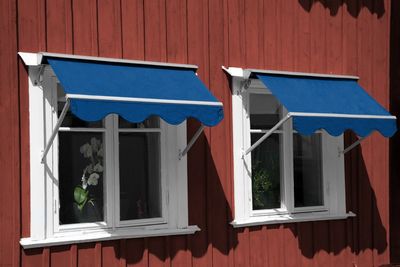 Enfärgat blå markisväv på falurött hus
