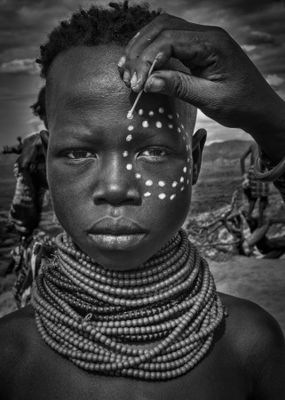 Painting the face of a karo tribe girl (Omo Valley-Ethiopia)