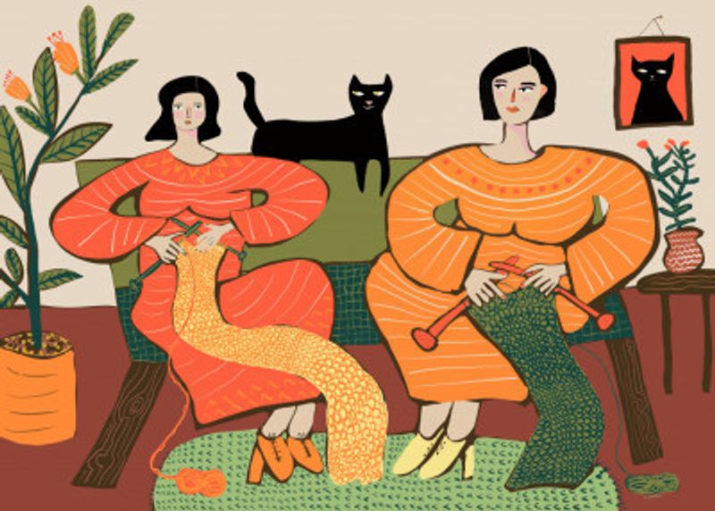 Women knitting on couch with black cat