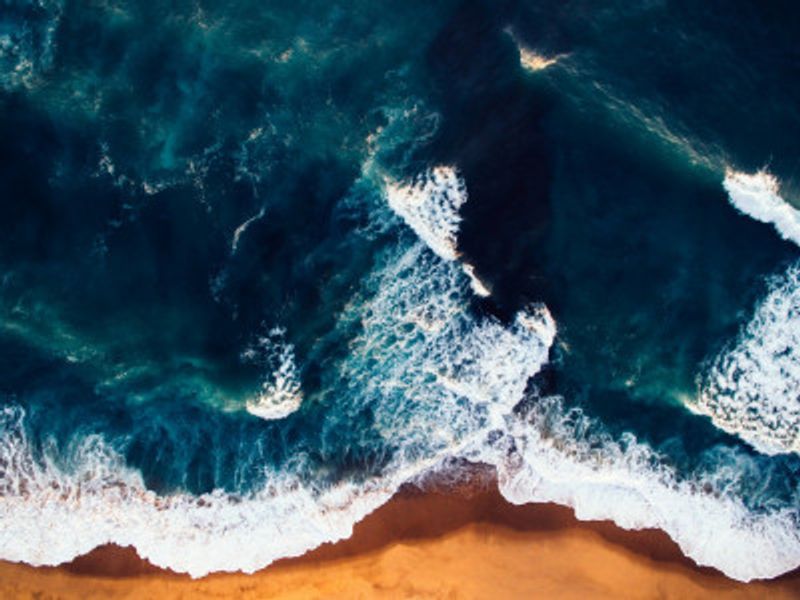 Vibrant Ocean Waves Against A Golden Sandy Beach