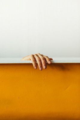 Hand Gently Gripping A White Ledge Above