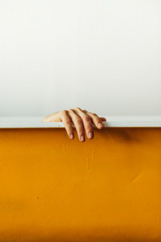 Hand Gently Gripping A White Ledge Above