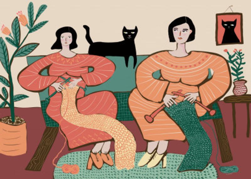 Women knitting on couch with black cat