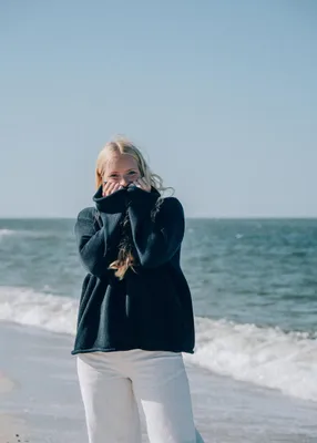Modell i marinblå stickad bomullströja vid havet