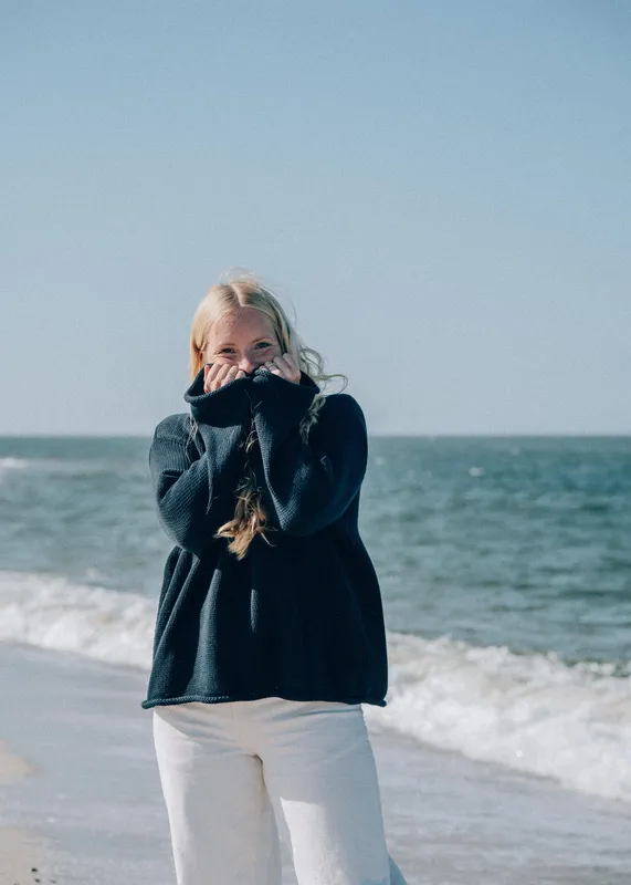 Modell i marinblå stickad bomullströja vid havet