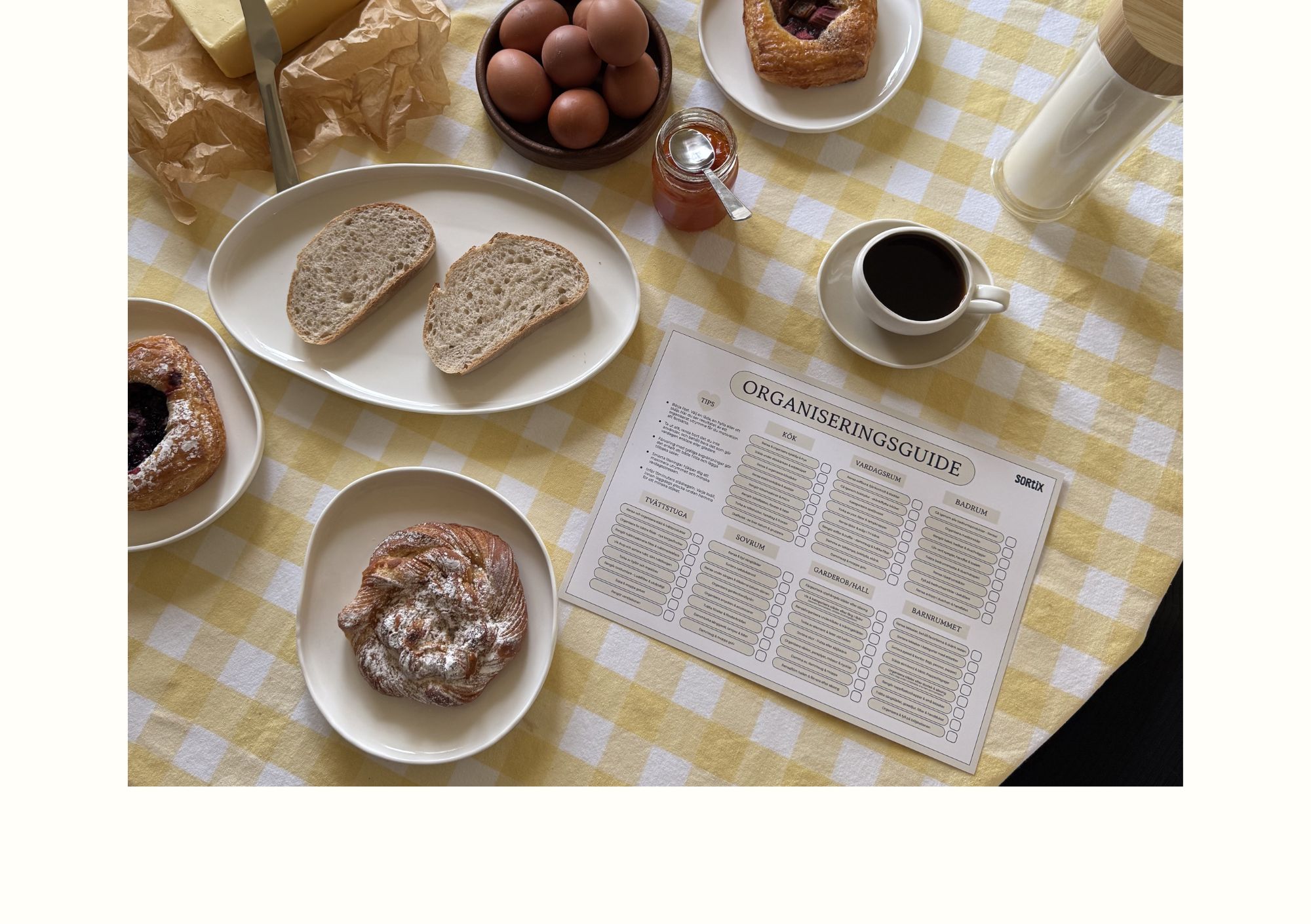 En inspirerande frukostmiljö med kaffe och bakverk där Sortix organiseringsguide ligger på bordet som en del av en harmonisk morgonrutin.