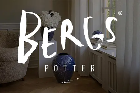 Två blå keramikvaser från Bergs Potter med vit blomdekor på vit radiatorhylla i ljust rum med trägolv och naturligt ljus.