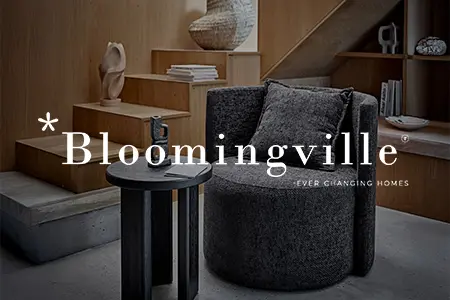 Mörkgrå snurrfåtölj från Bloomingville bredvid svart sidobord i modern inredning med trätrappa och dekorativa hyllor.
