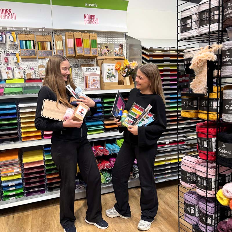 Två personer, Emelie och Jossan, som håller upp flera varor ur sortimentet hos Cria