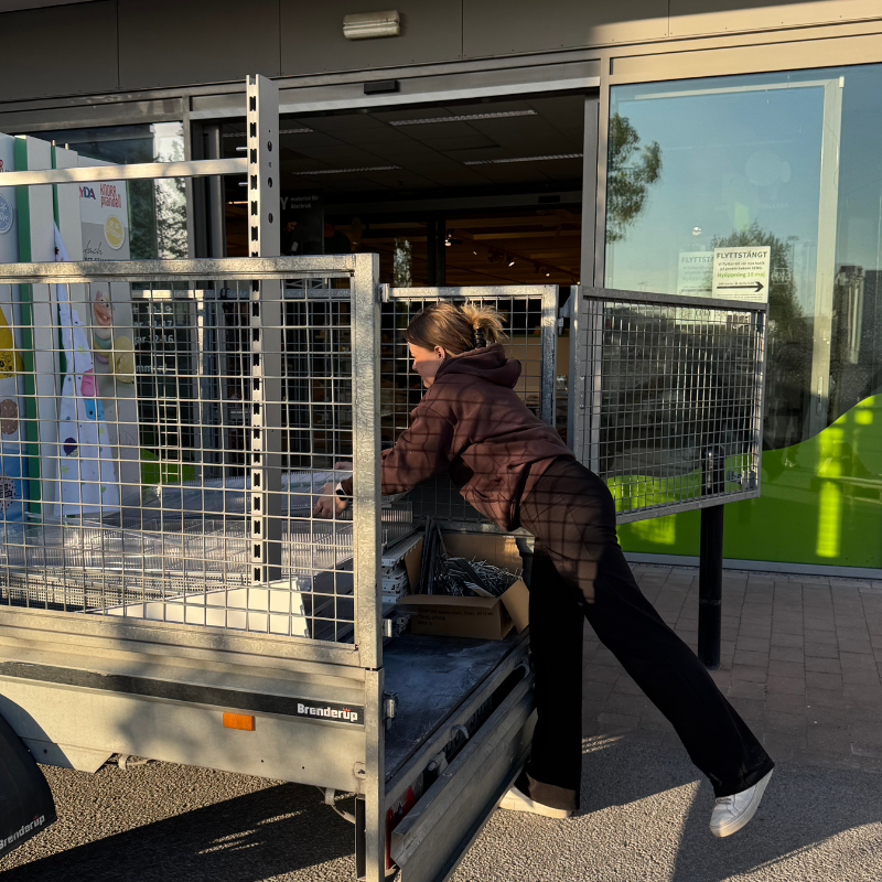 Emelie lyfter in hyllor i släp
