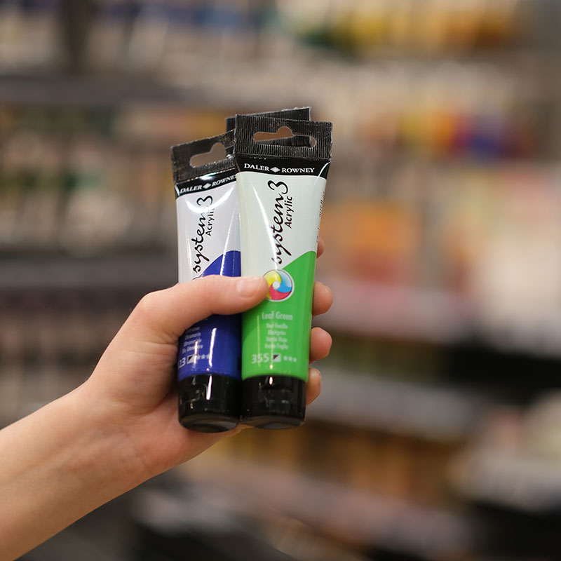 Tre stycken tuber med System3 mot suddig butiksbakgrund