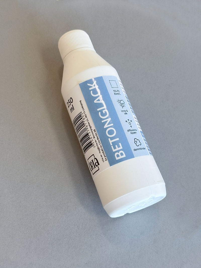 En flaska, 250 ml, med betonglack på en matt betongyta.