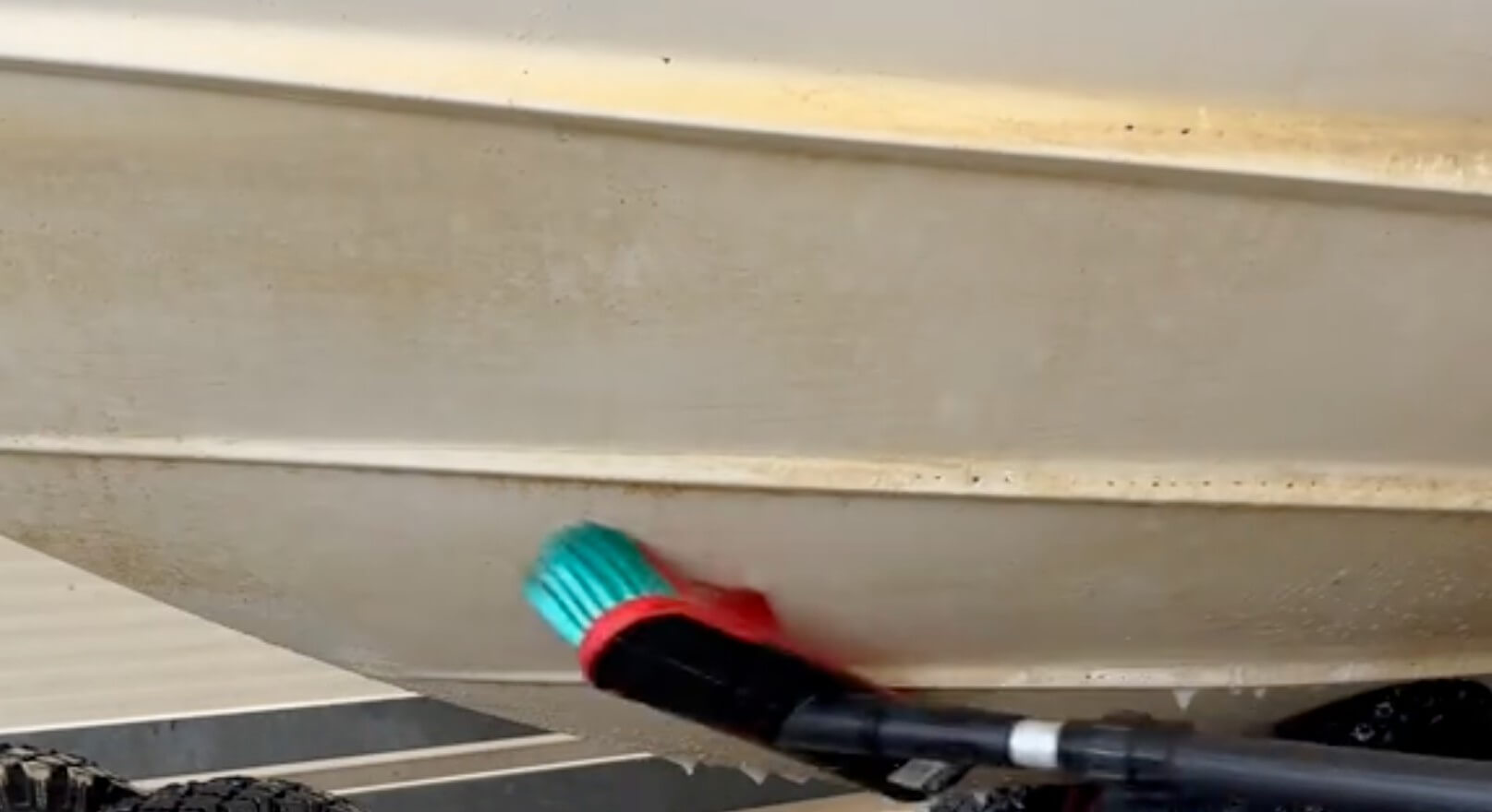skrubbar vattenlinjen på båt med lång borste och syratvätt
