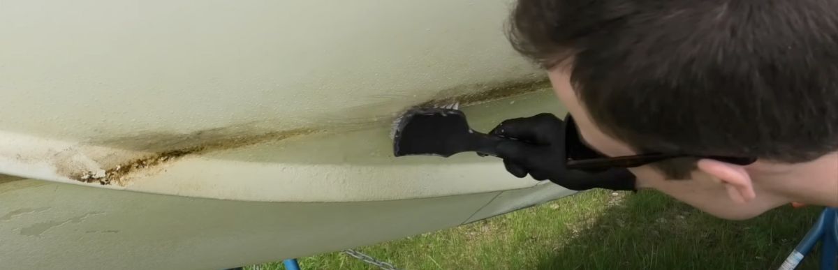 skrubbar rent vattenlinje på båt med borste och alkalisk avfettning