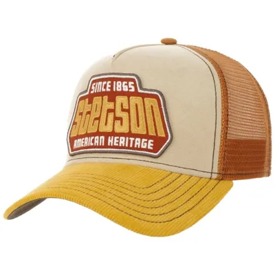 En trucker keps med böjd skärm. Skärmen är gul, fronten är beige och baksidan är orange/rostig. På fronten är Stetson logga med brodyr på " Since 1865 - American Heritage".