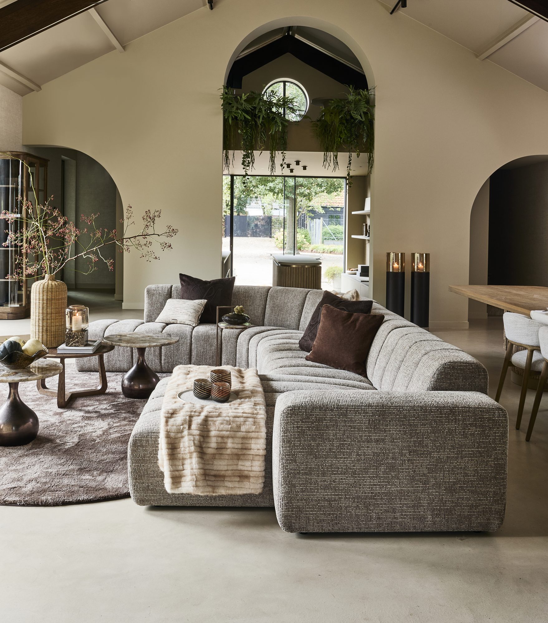 Riviera Maison vardagsrum med stor soffa under ett högt takvalv